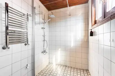 a white tiled bathroom with a shower and a window at Historical Greco-Ottoman Pavilion near Tram in Fatih in Istanbul