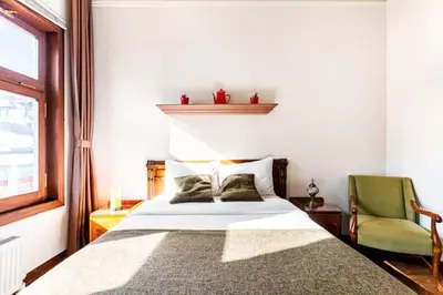 a bedroom with a bed and a green chair at Historical Greco-Ottoman Pavilion near Tram in Fatih in Istanbul
