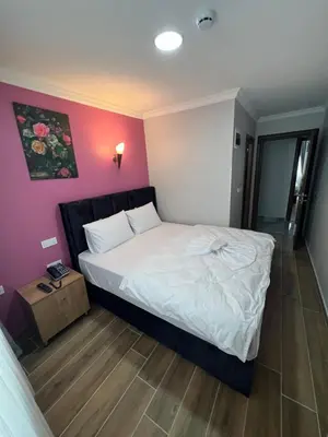a bedroom with a white bed and a pink wall at MİRHAN HOTEL in Istanbul