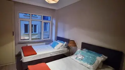two beds in a small room with a window at Tam Merkezde Yepyeni Bir Daire in Istanbul