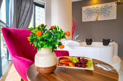 a table with a plate of fruit and a vase with flowers at Parla Suite Hotel in Esenyurt