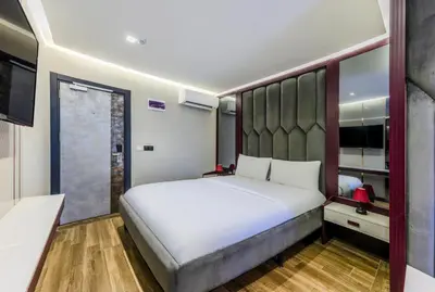 a bedroom with a large white bed and a television at Heaven Premium Hotel Restaurant & Airport Shuttle in Arnavutköy