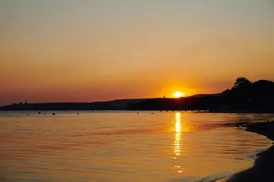 a sunset on a beach with the sun setting at Parmos Otel in Erdek