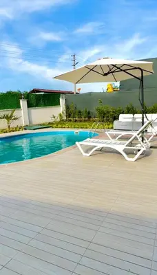 a white chair and an umbrella next to a pool at Begonvil Konaklama in Sapanca