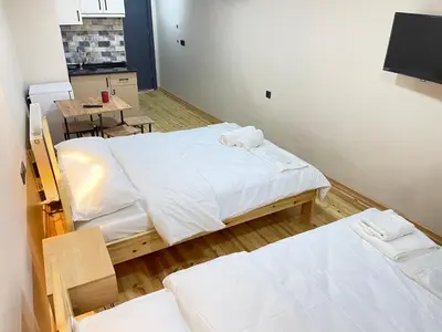 a room with two beds and a table and a kitchen at La Perato in Istanbul